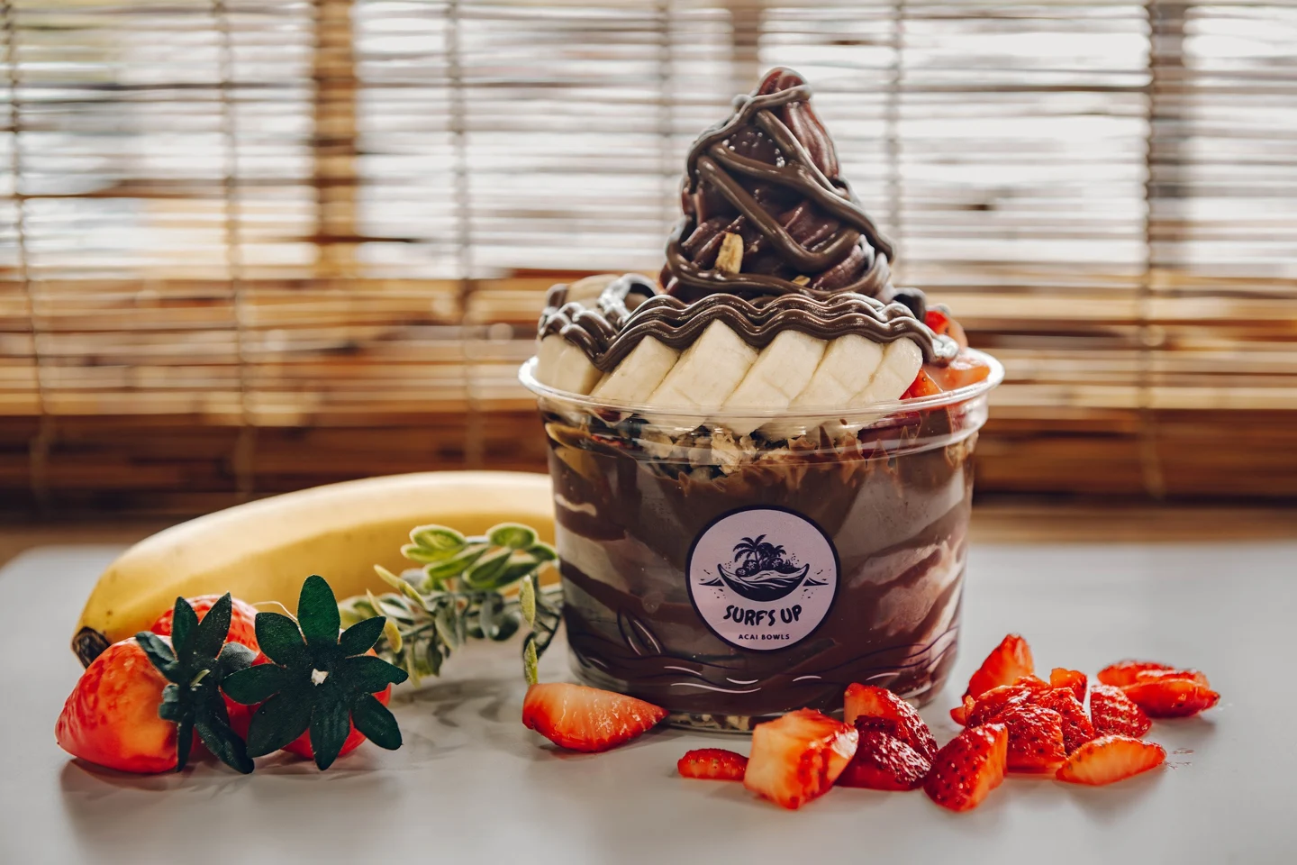 Açaí bowl with sliced banana, strawberries and chocolate drizzle